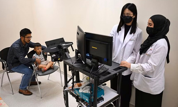  ​Clinical research coordinators conducting a demonstration of a research study on a child to study the time he takes to react to a stimulus. ST PHOTO SHINTARO TAY 